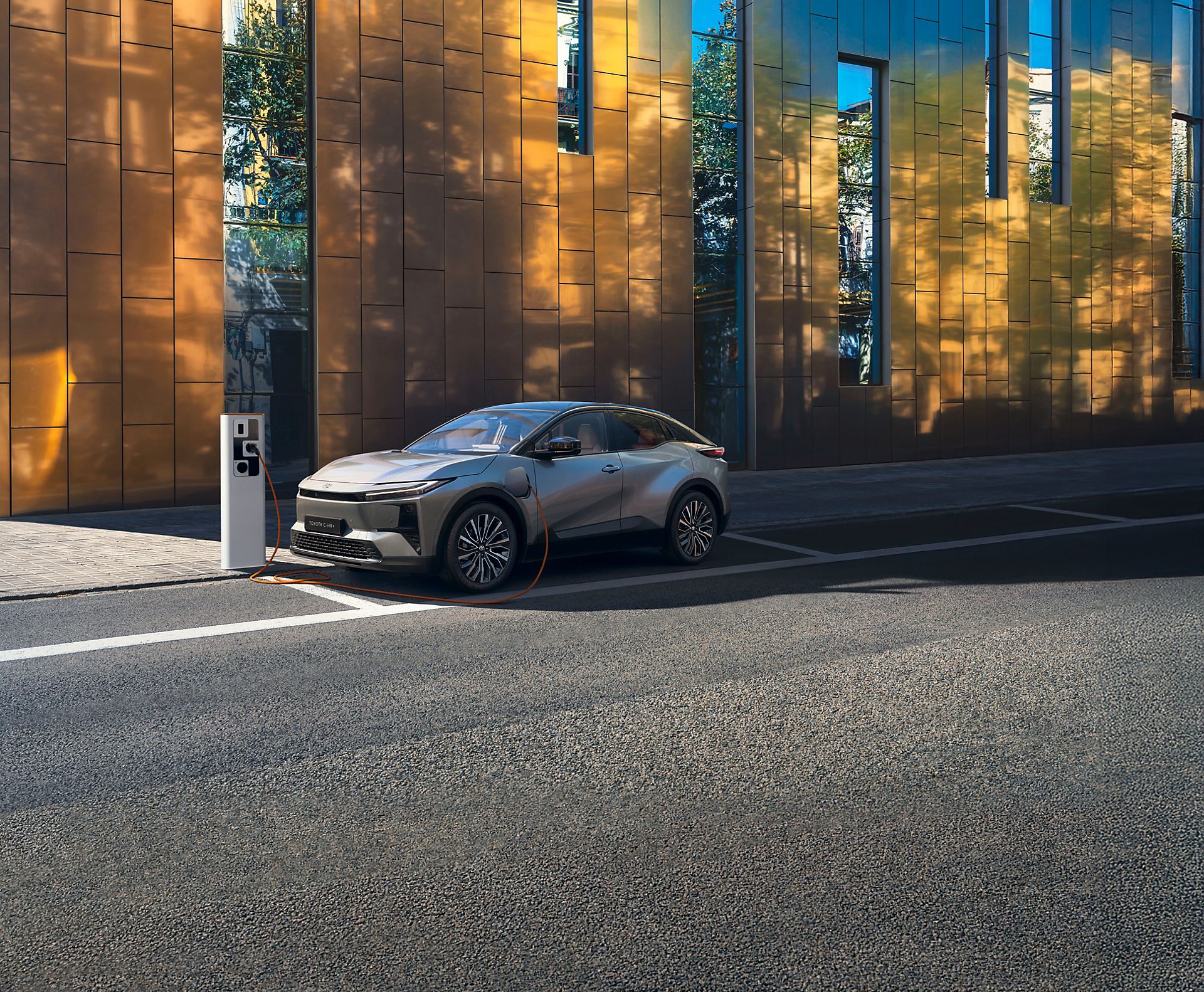 Un Toyota C-HR+ recharge à l’aide d’une borne de recharge publique en rue