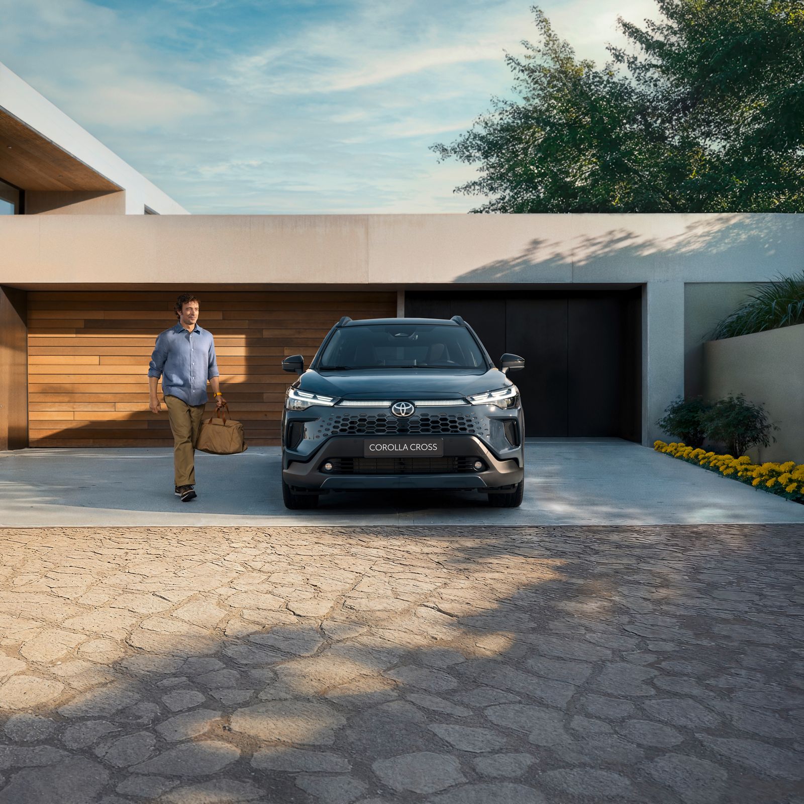 A Toyota Corolla Cross owner outside a stylish, modern home