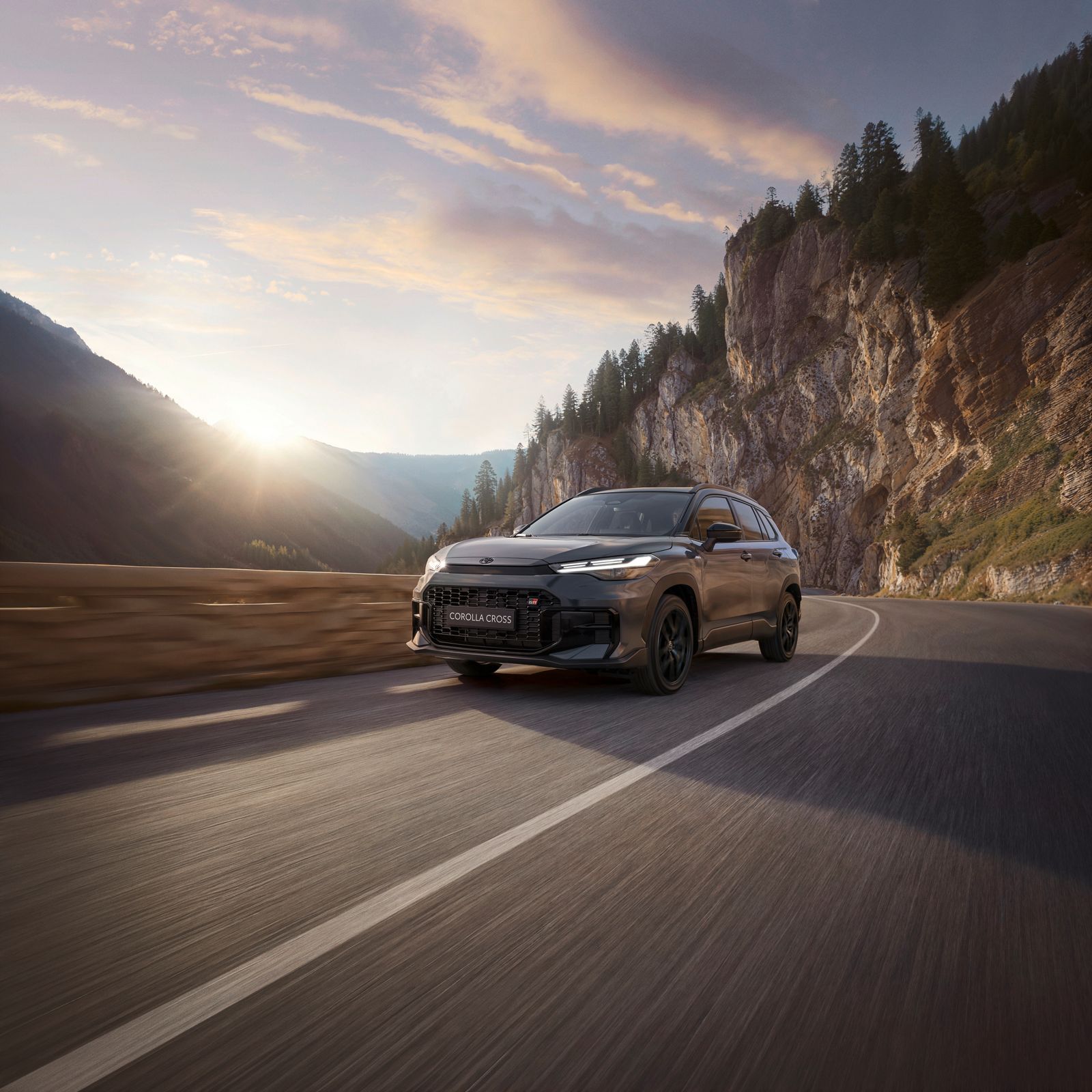 A Corolla Cross drives a scenic highway in the hills 