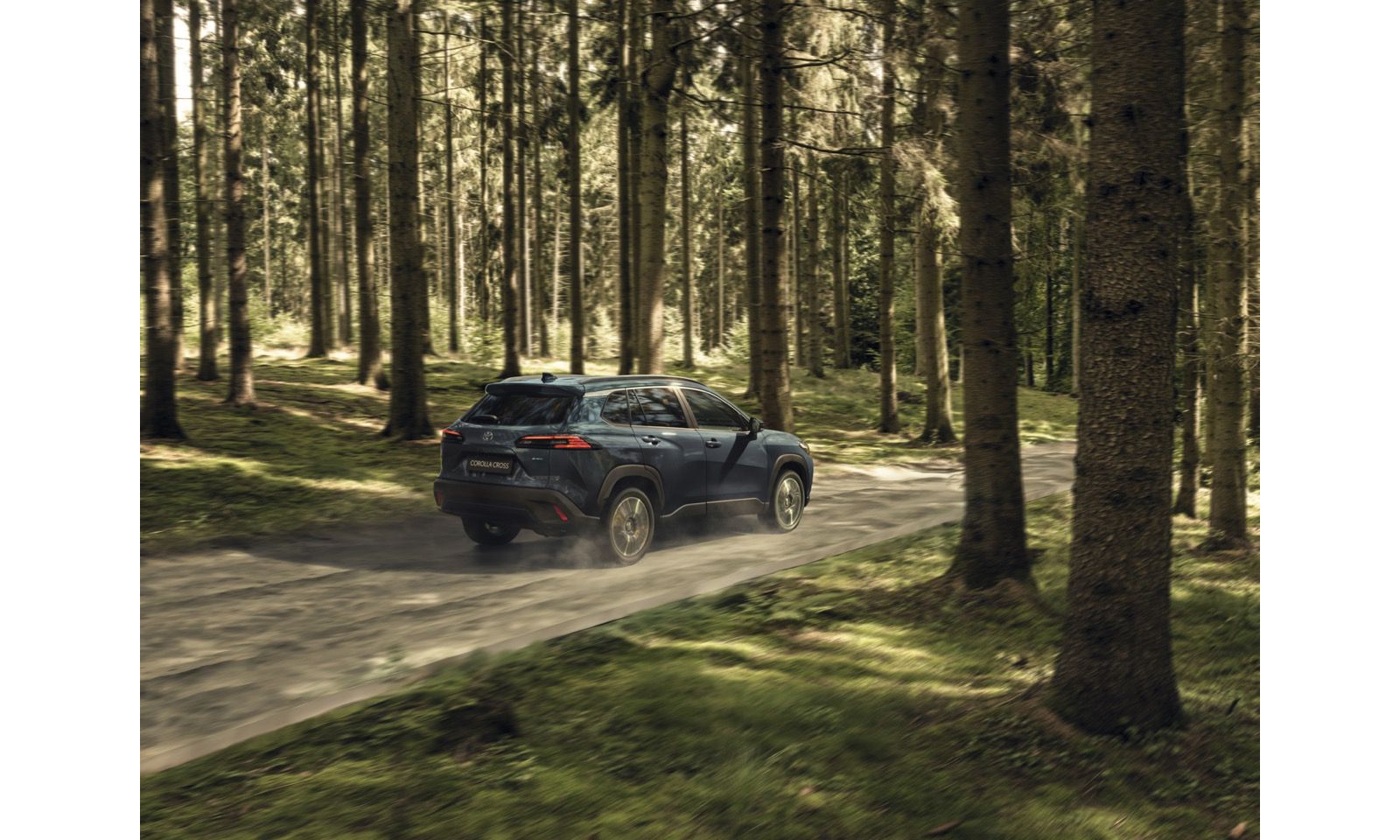 Toyota Corolla Cross su una strada sterrata in mezzo alla foresta