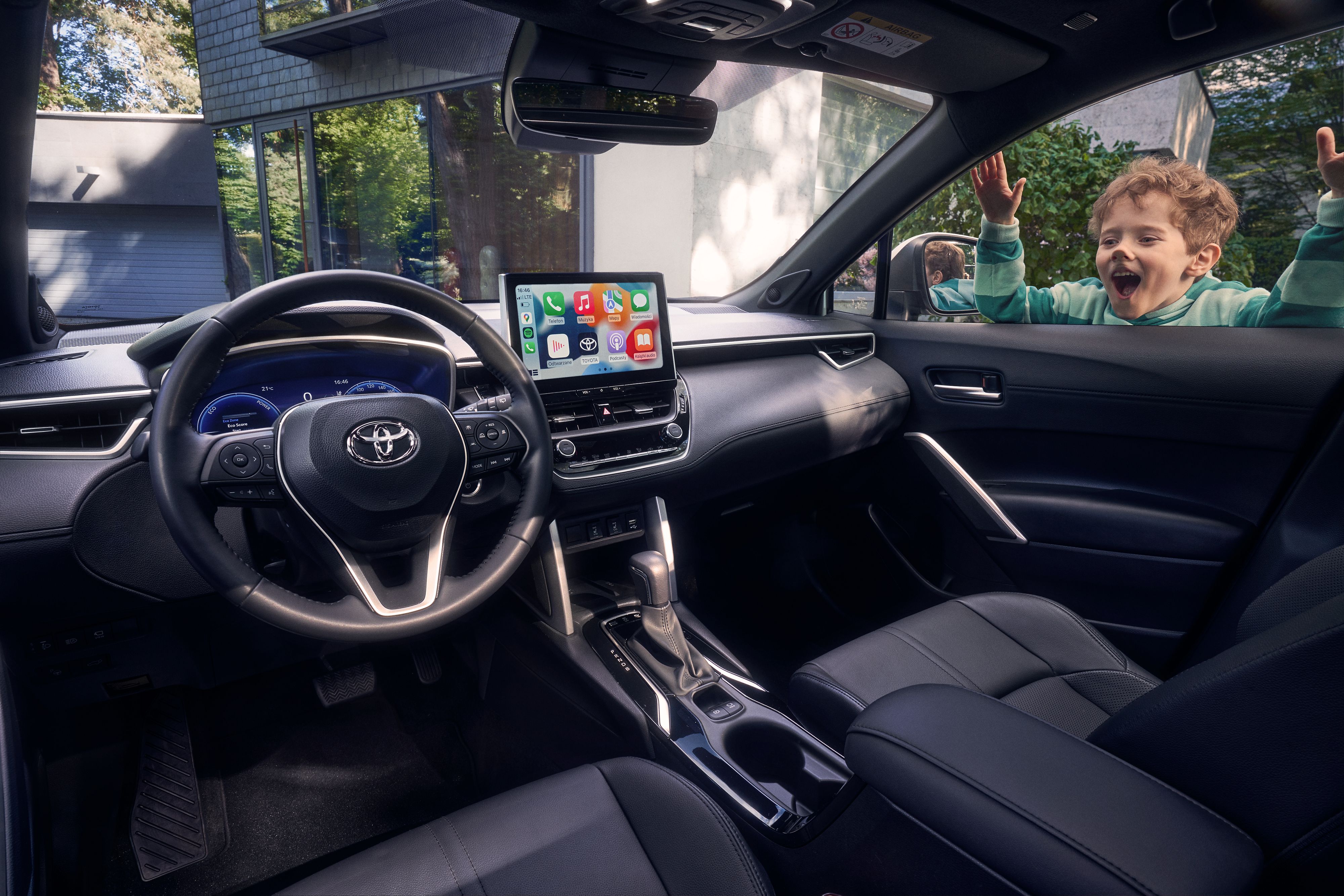 Innenansicht des Toyota Corolla Cross, am rechten Fenster schaut ein Kind, das das Gesicht gegen das Glas presst hindurch