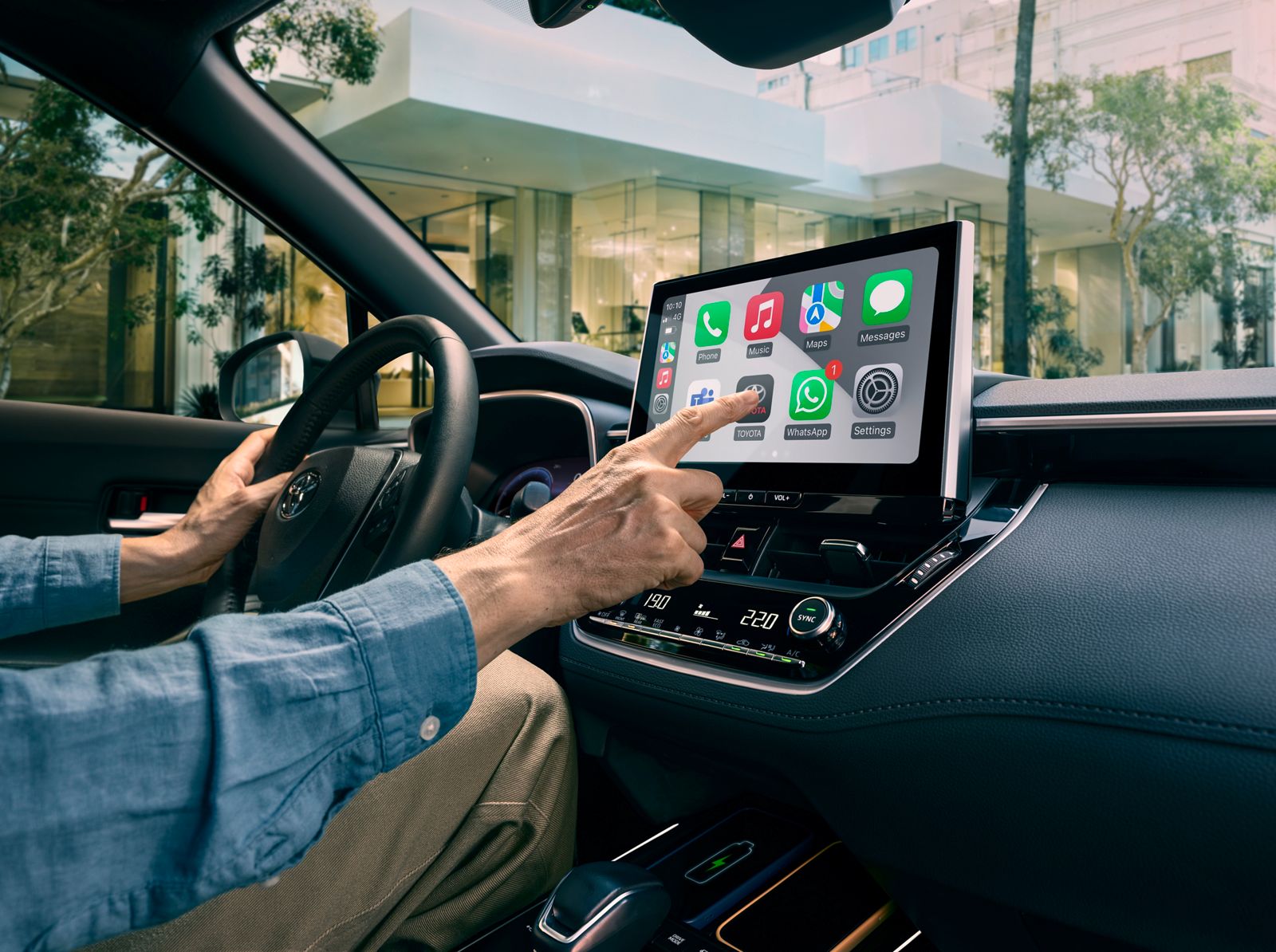 A Corolla Cross owner uses the multimedia touchscreen