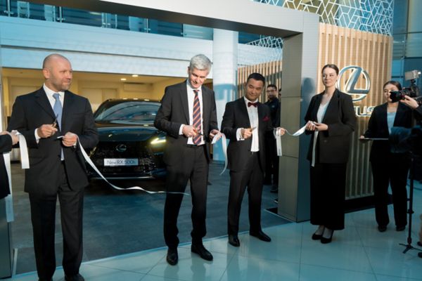 A group of people surrounding a Lexus