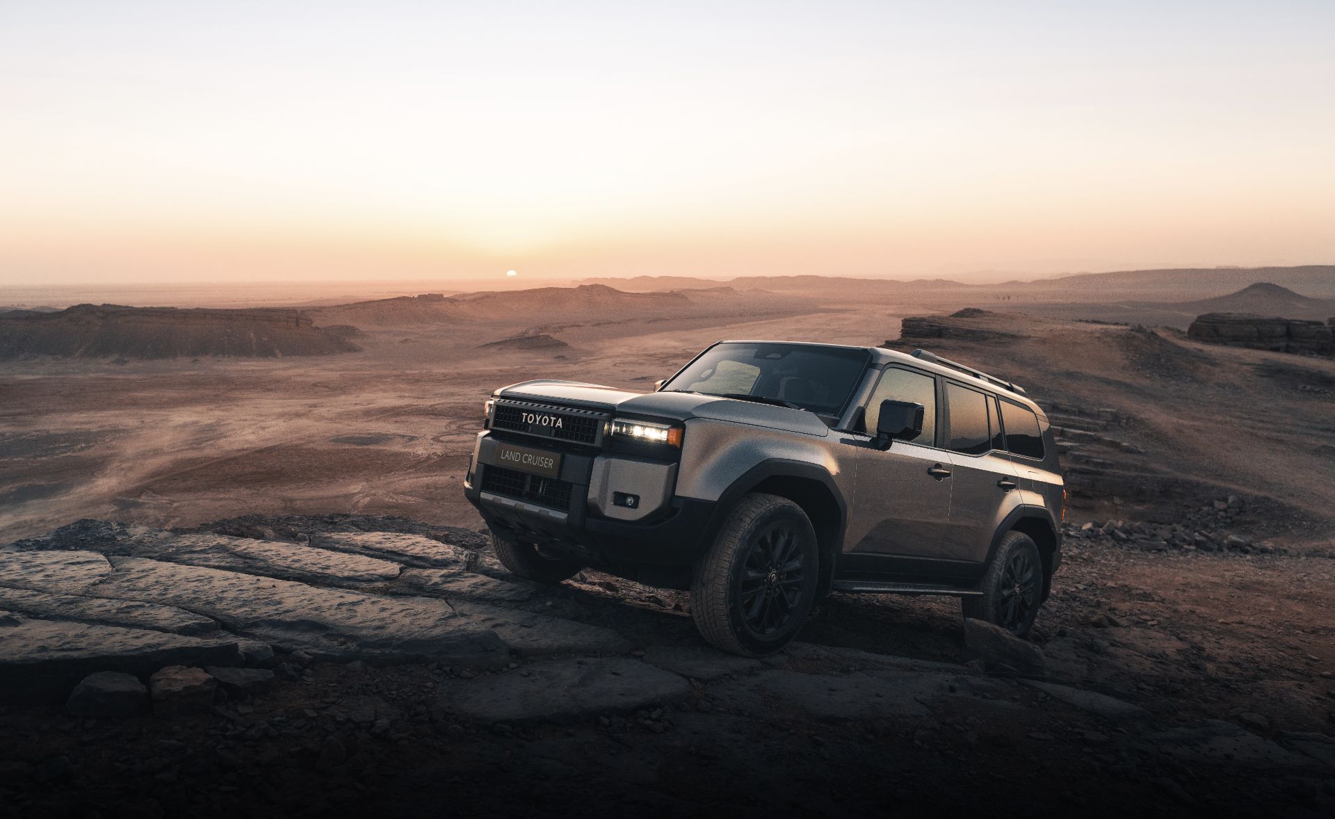 Toyota Land Cruiser na bezdrożach wjeżdża po skałach pod górę.