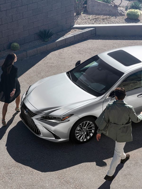 A man and woman wallking towards a Lexus ES 300h