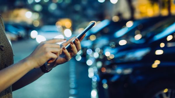 Hands holding a phone in front of row of cars