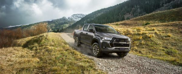 Grauer Toyota Hilux fährt einen Schotterweg in den Bergen herunter