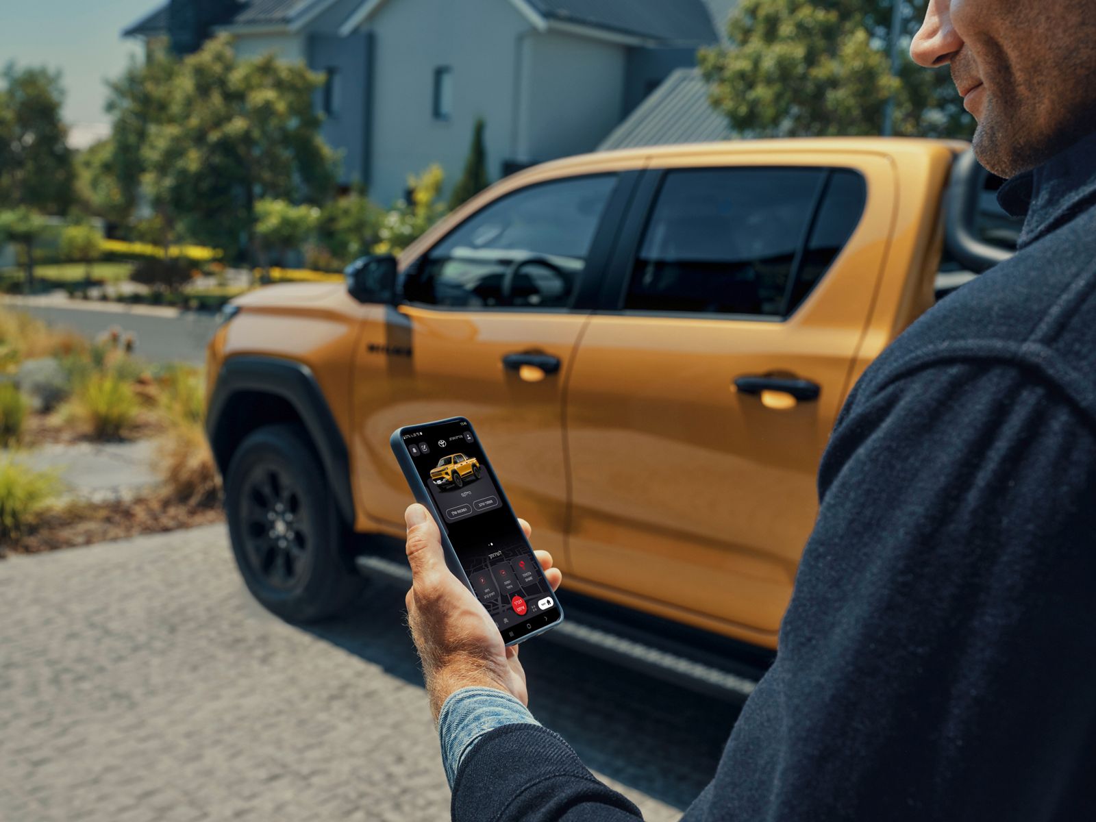 Hilux owner using a mobile phone to interact with the vehicle.
