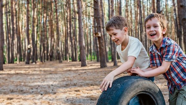 Happy children playing with a tire in the woods