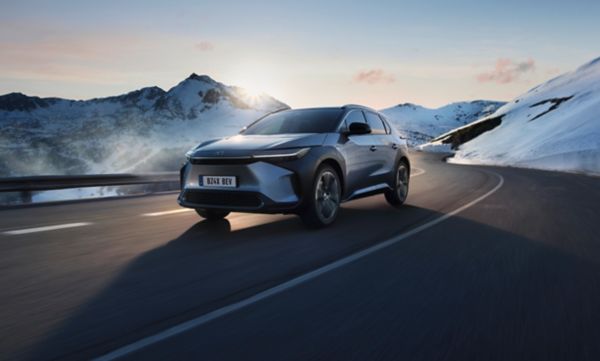 Ein Toyota bZ4X fährt auf einer kurvigen Straße in einer beschneiten Berglandschaft