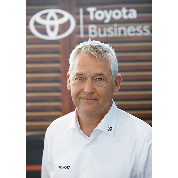 Heiko Peter Taubert trägt ein Hemd mit dem Toyota-Logo und steht vor einem Hintergrund mit dem Markenzeichen: Toyota Business