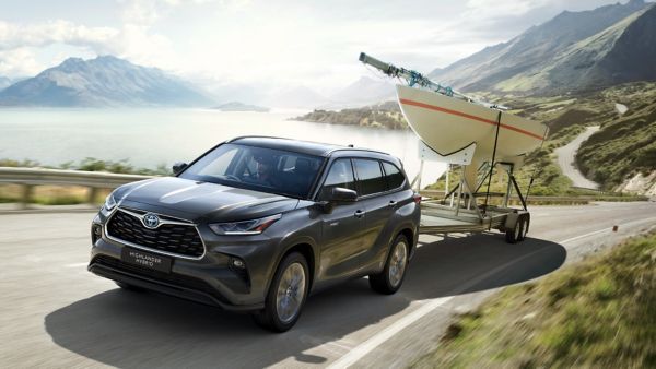 Toyota Highlander driving along a road towing a boat