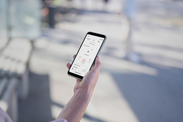 Inimene hoiab käes nutitelefoni, milles on näha MyToyota rakenduse veebileht. Kuvatakse kaugjuhitava kliimaseadme, lukustamise ja lukust avamise ning ohutulede funktsioone.