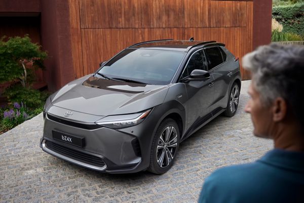 Jovem mulher descontraída Toyota encostada a um Toyota