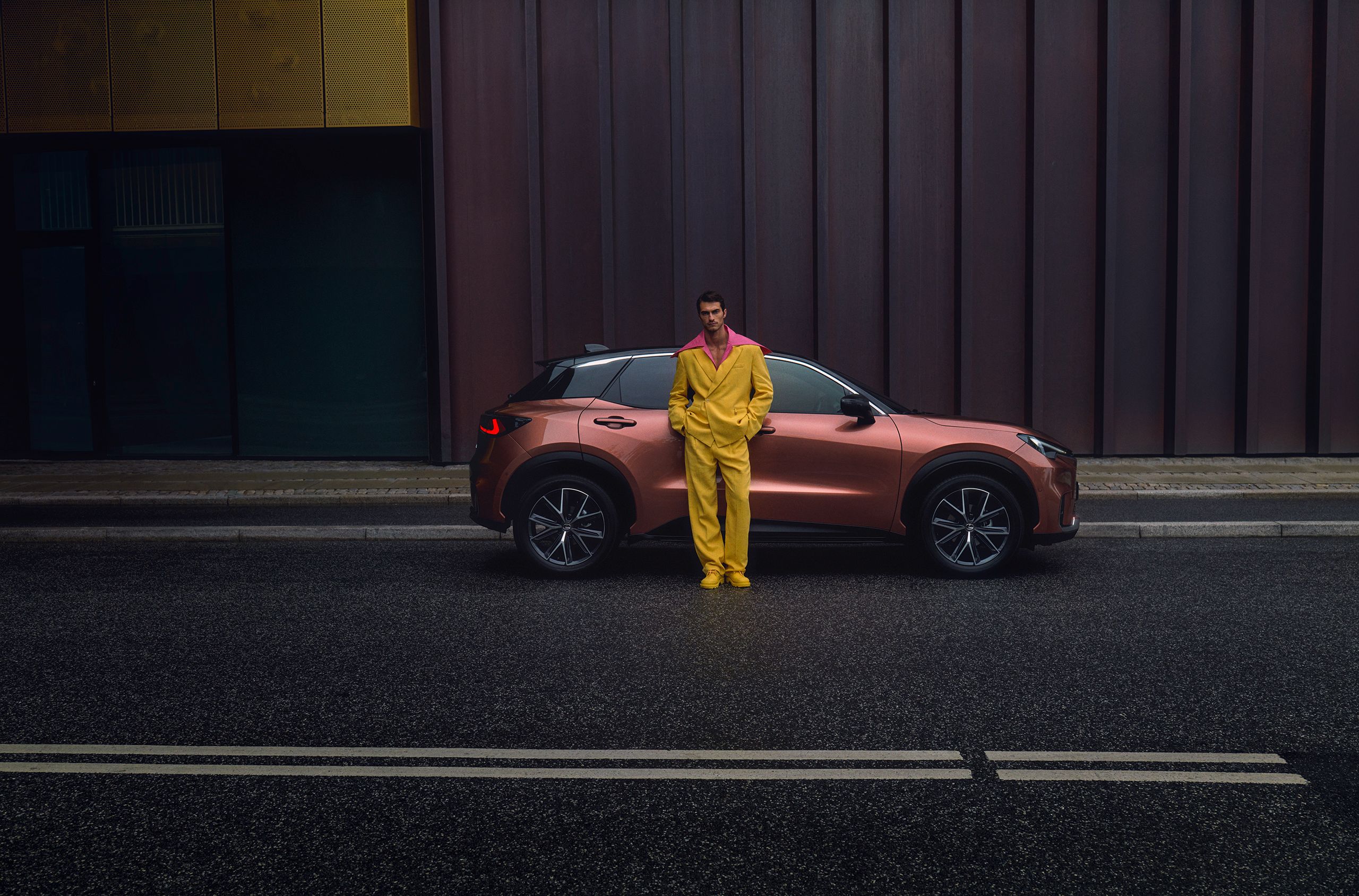Automóvel Lexus parado com um homem vestido de amarelo encostado na lateral do carro