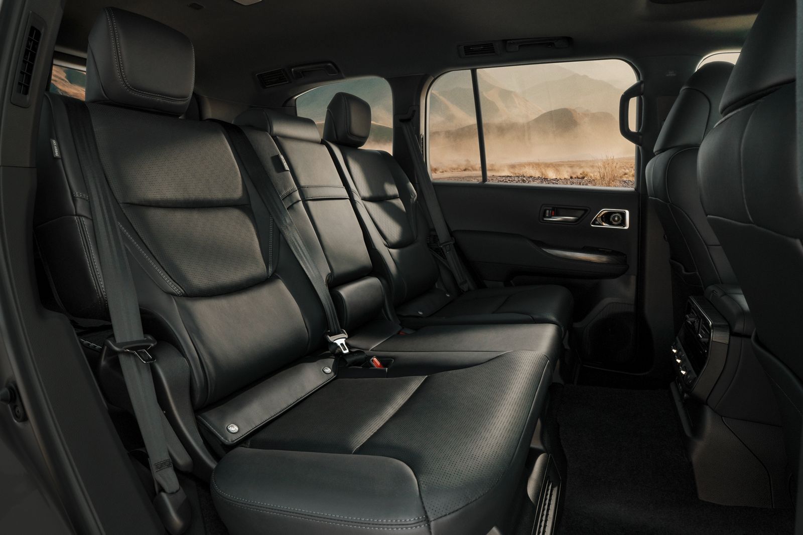 Land Cruiser 300’s spacious rear seats in premium black leather, with mountain views through windows.