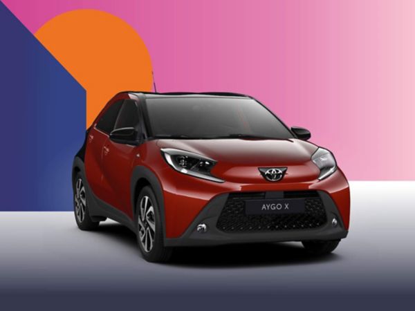 Ein roter Toyota Aygo X Teamplayer auf einem bunten Hintergrund.