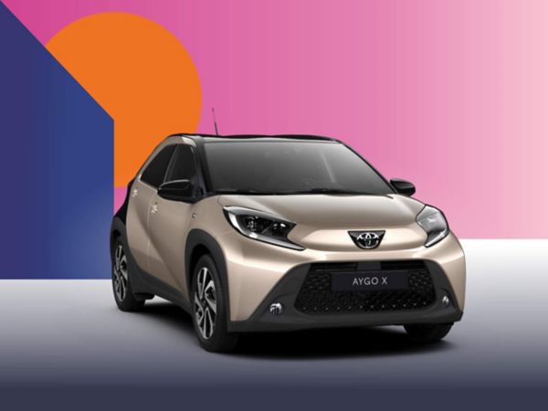 Ein beiger Toyota Aygo X Teamplayer auf einem bunten Hintergrund.