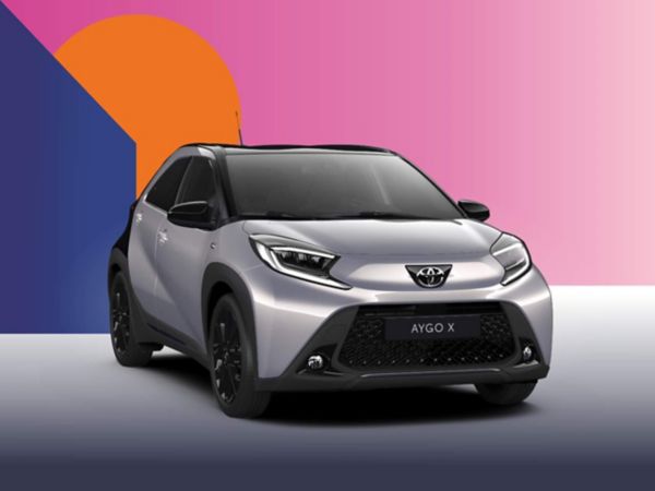 Ein silbener Toyota Aygo X Teamplayer auf einem bunten Hintergrund.