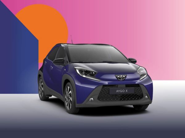 Ein blauer Toyota Aygo X Teamplayer auf einem bunten Hintergrund.