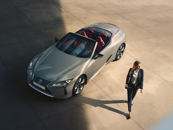 A person standing next to a Lexus LC Convertible