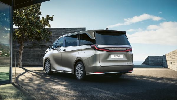 Ein eleganter Lexus LM Minivan, der im Freien geparkt ist und sein modernes Design mit einem Panoramablick auf den Himmel und einen Baum in der Nähe zur Geltung bringt.