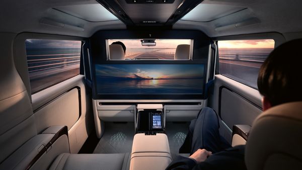 Luxuriöses Interieur eines Lexus LM, in dem sich ein Fahrgast entspannt, während er auf einem großen Display einen malerischen Sonnenuntergang betrachtet