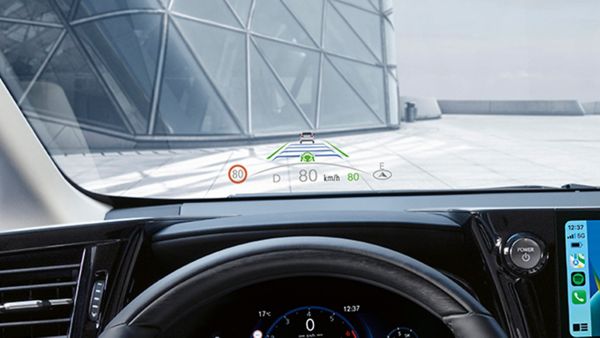 Heads-up-Display in einem Auto, das die Geschwindigkeit bei 80 km/h, Navigationsanweisungen und Straßenmerkmale in der Nähe anzeigt, mit einem modernen Gebäude im Hintergrund.