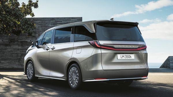 Ein eleganter Lexus LM Minivan, der im Freien geparkt ist und sein modernes Design mit einem Panoramablick auf den Himmel und einen Baum in der Nähe zur Geltung bringt.