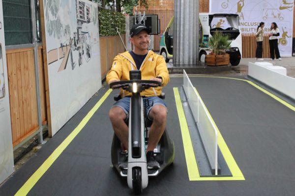 Ein junger Mann fährt mit einem kleinen elektrischen Fahrzeug für Gehbehinderte auf einer ausgewiesenen Teststrecke des Ausstellungsgeländes