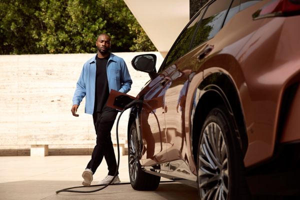 Eine Person geht zu einem Lexus, der zum Laden angeschlossen ist