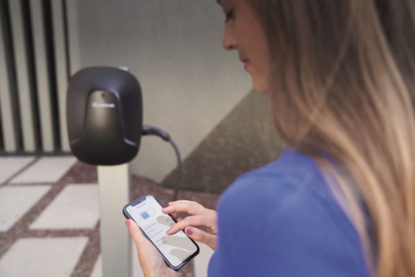 Person standing next to charge point on phone