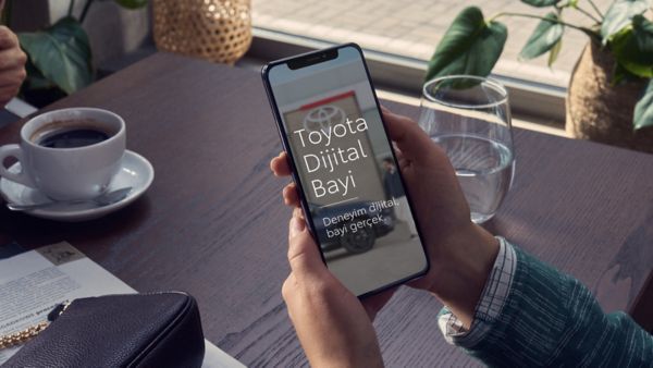 Ekranında "Toyota dijital bayi" yazan akıllı telefon tutan bir kullanıcı