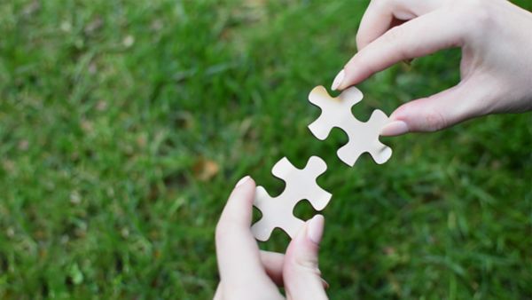 Mains assemblant deux pièces d’un puzzle