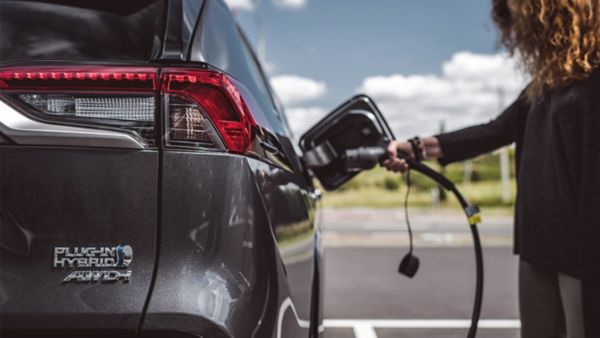 Woman plugging Toyota RAV4 plug-in hybrid