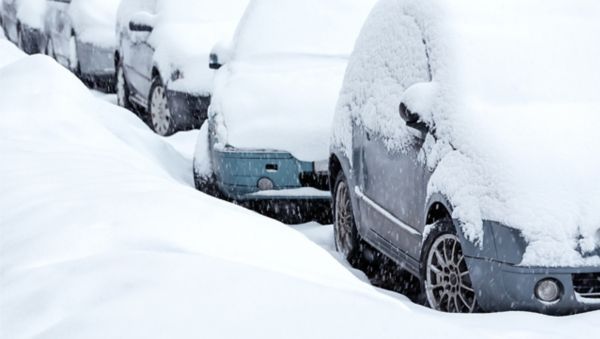 vollständig von Schnee bedeckte Fahrzeuge stehen in einer Reihe