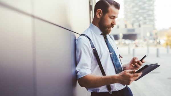 Un uomo usa uno smartphone e un tablet digitale