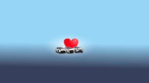 Drei weiße Autos vor einem großen roten Herz auf blauem Hintergrund – symbolisch für eine emotionale Verbindung zum Fahrzeug.