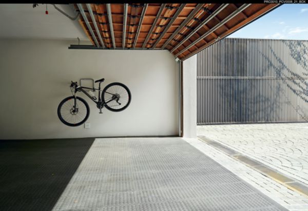 Polkupyörä autotallin seinällä roikkumassa.