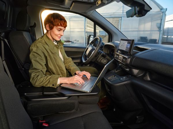 Person auf dem Fahrersitz arbeitet auf einem Laptop, das auf der Mittelkonsole steht