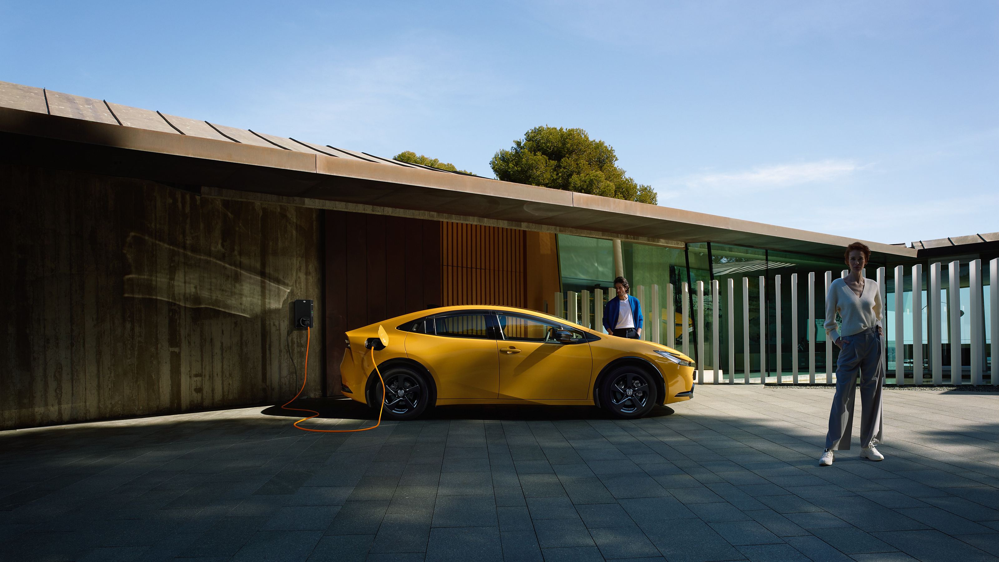 Gelber Toyota Prius steht unter einem Carport und lädt an einer Ladesäule