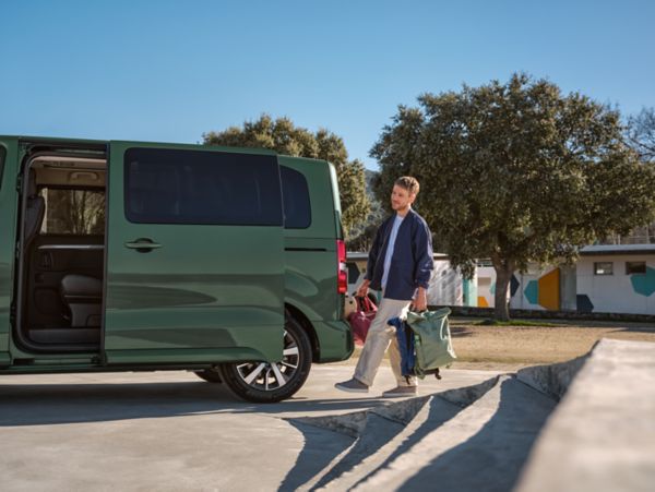 Mann mit Koffer in der Hand auf dem Weg zu seinem Toyota Proace Verso