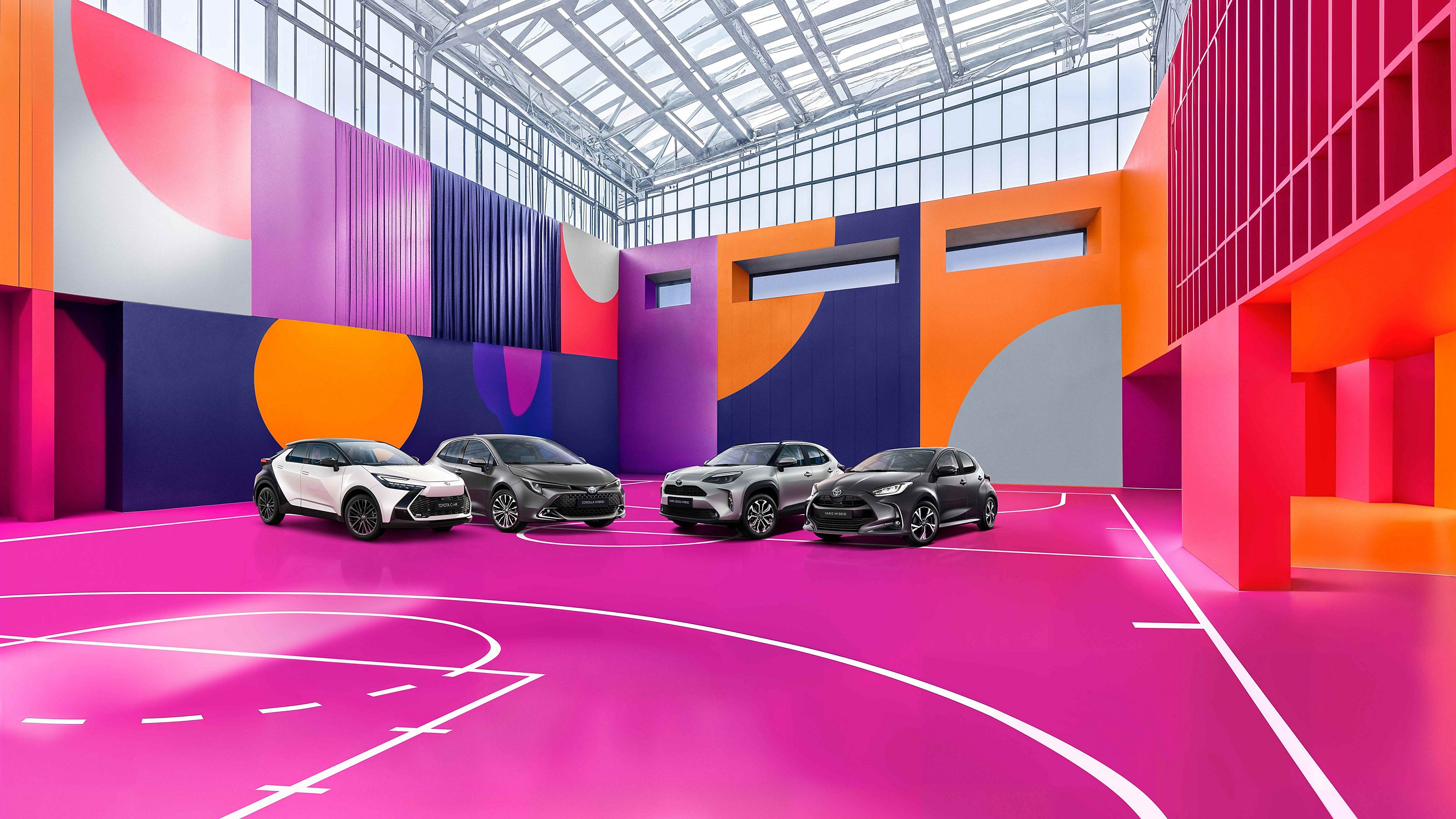 Vier Toyota Fahrzeuge auf dem Innenhof eines modernen Gebäudes mit Glasfront, Bildtext: „LAST MINUTE DEALS, 1,99% EASY FINANZIERUNG“