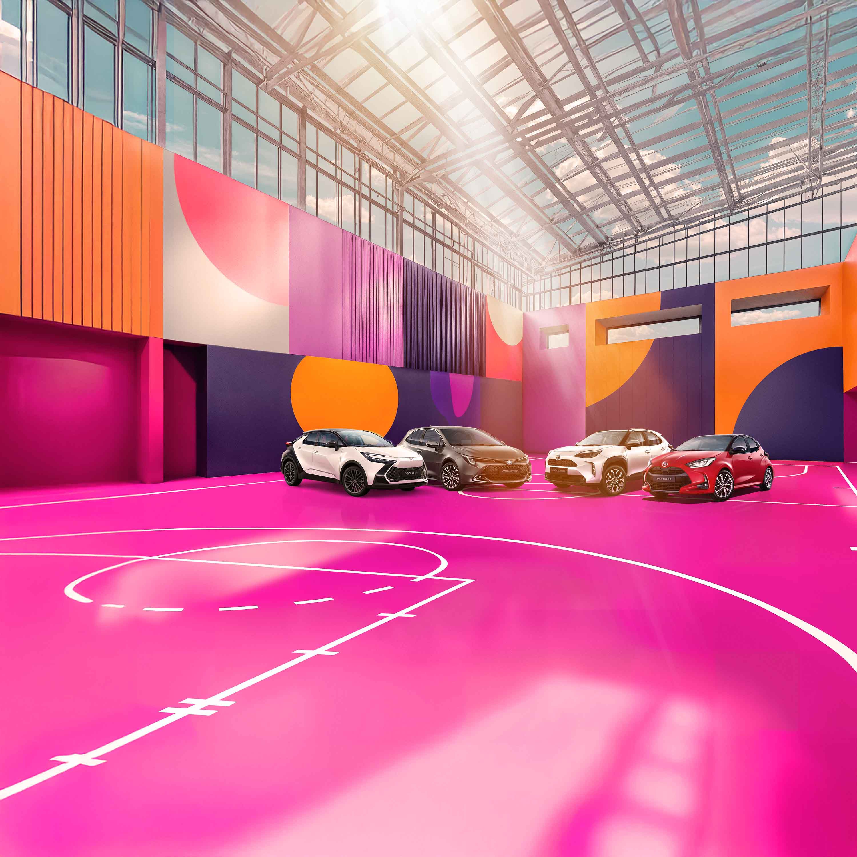 Ein weißer Toyota C-HR, ein grauer Corolla, ein weißer Yaris Cross und ein roter Yaris stehen auf einem bunten, mit lilanen, roten und blauen Mustern versehenen Basketballplatzes