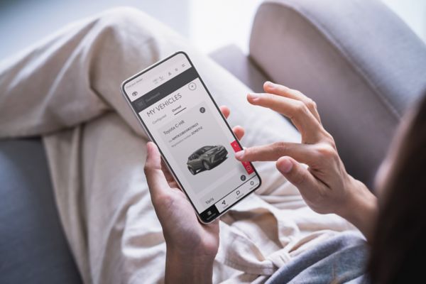 O femeie atinge ecranul smartphone-ului ei. Afiseaza un Toyota C-HR pe pagina Vehiculele mele de pe site-ul personal Toyota.