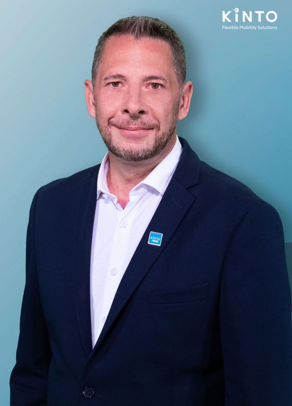 Matthias Butros trägt ein Sakko mit dem Kinto-Logo und steht vor einem Hintergrund mit dem Markenzeichen: Kinto
