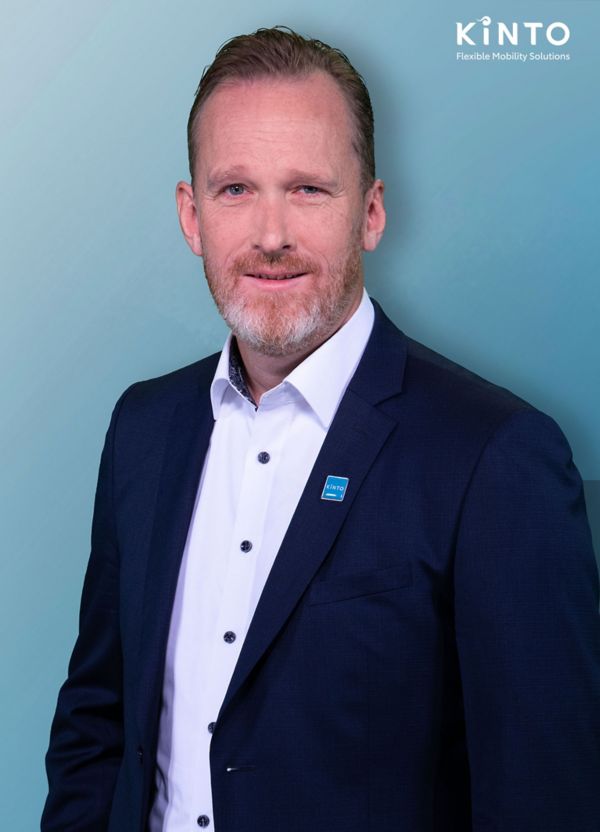 Matthias Kaiser trägt ein Sakko mit dem Kinto-Logo und steht vor einem Hintergrund mit dem Markenzeichen: Kinto