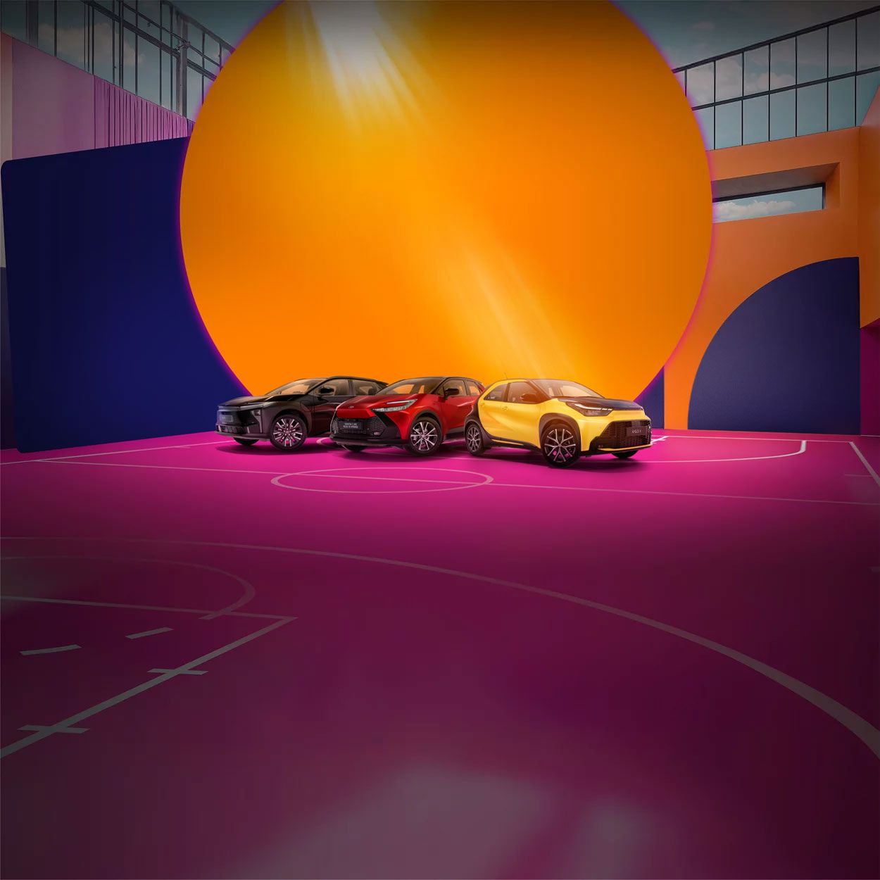 Vier Toyotas stehen auf einem pinken Basketballplatz, der von einer bunt bemalten Wand umgeben ist.