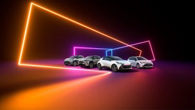 Vier moderne Fahrzeuge in Grau, Silber und Weiß stehen auf einem Boden mit Farbverlauf, umgeben von leuchtenden geometrischen Linien in Orange, Pink und Blau vor dunklem Hintergrund.