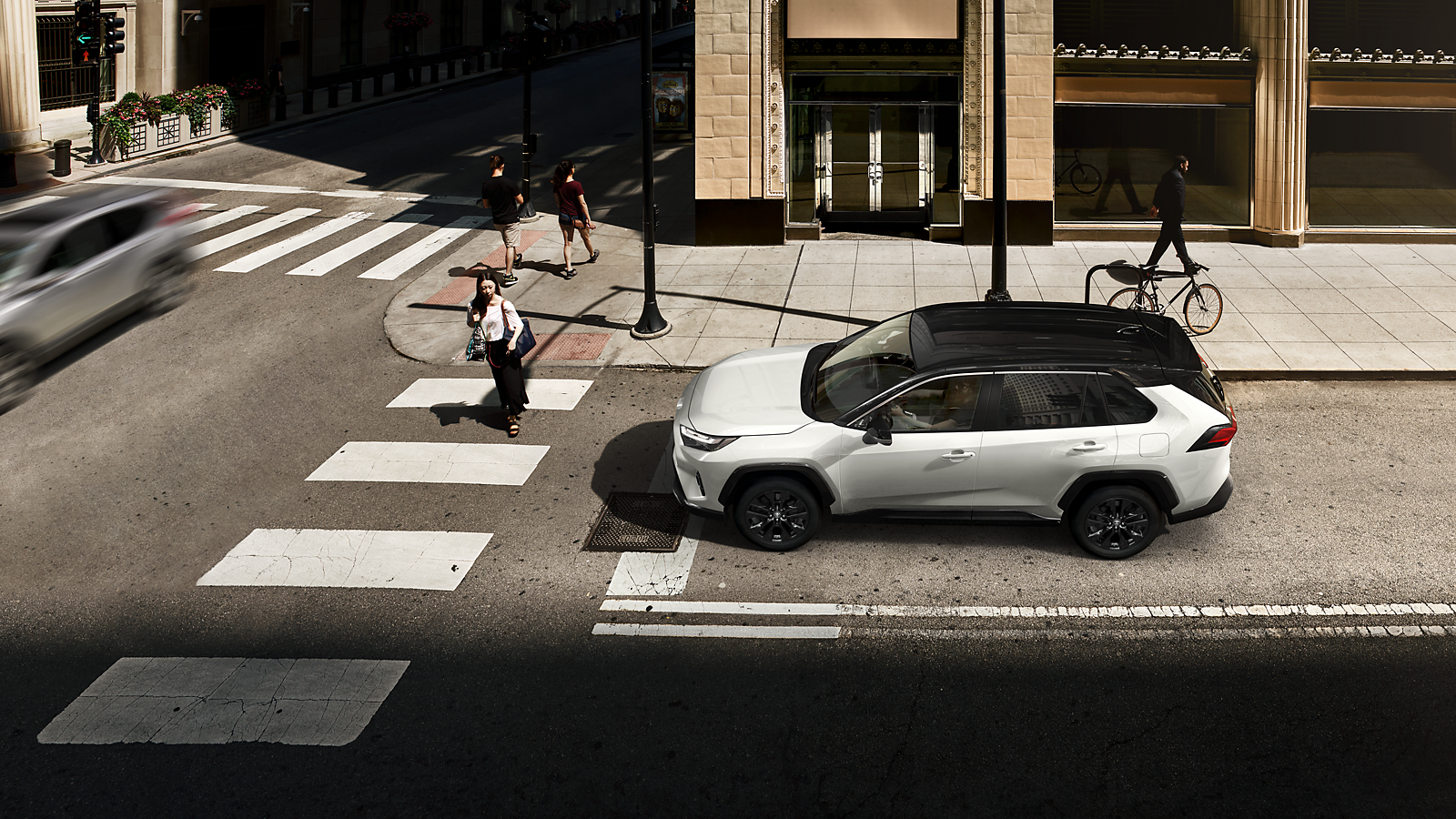 Un RAV4 percorre una strada di città illuminata dal sole